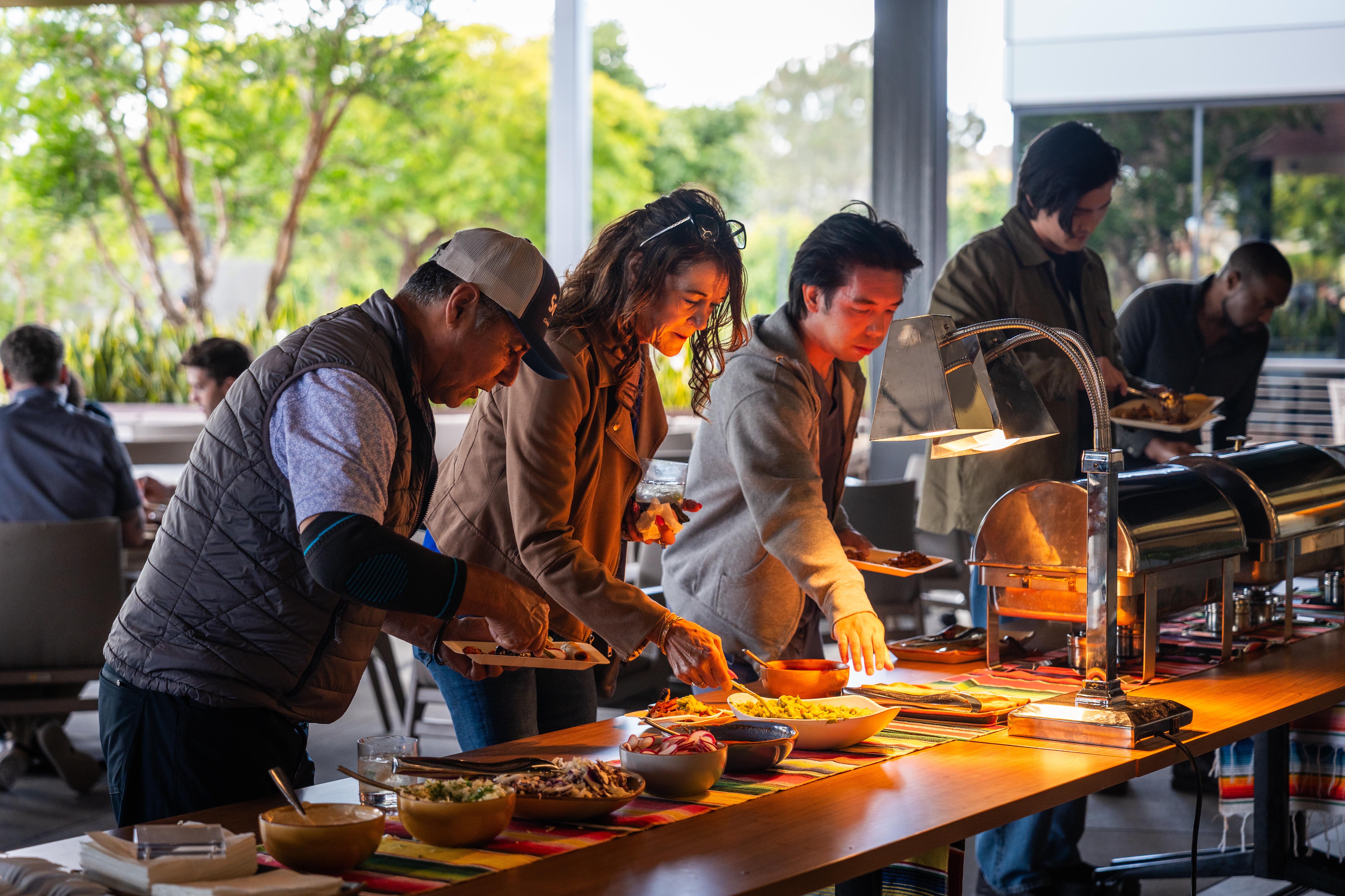 Guests selecting food from a catered buffet at a Joya Kitchen event.