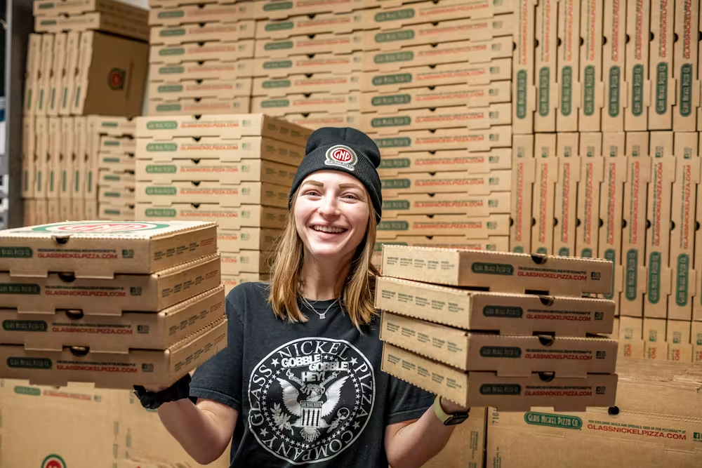 a woman holding a stack of pizza boxes