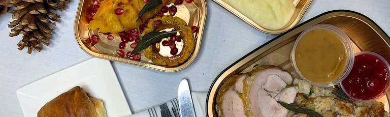 a box filled with thanksgiving dinner including turkey, mashed potatoes, squash