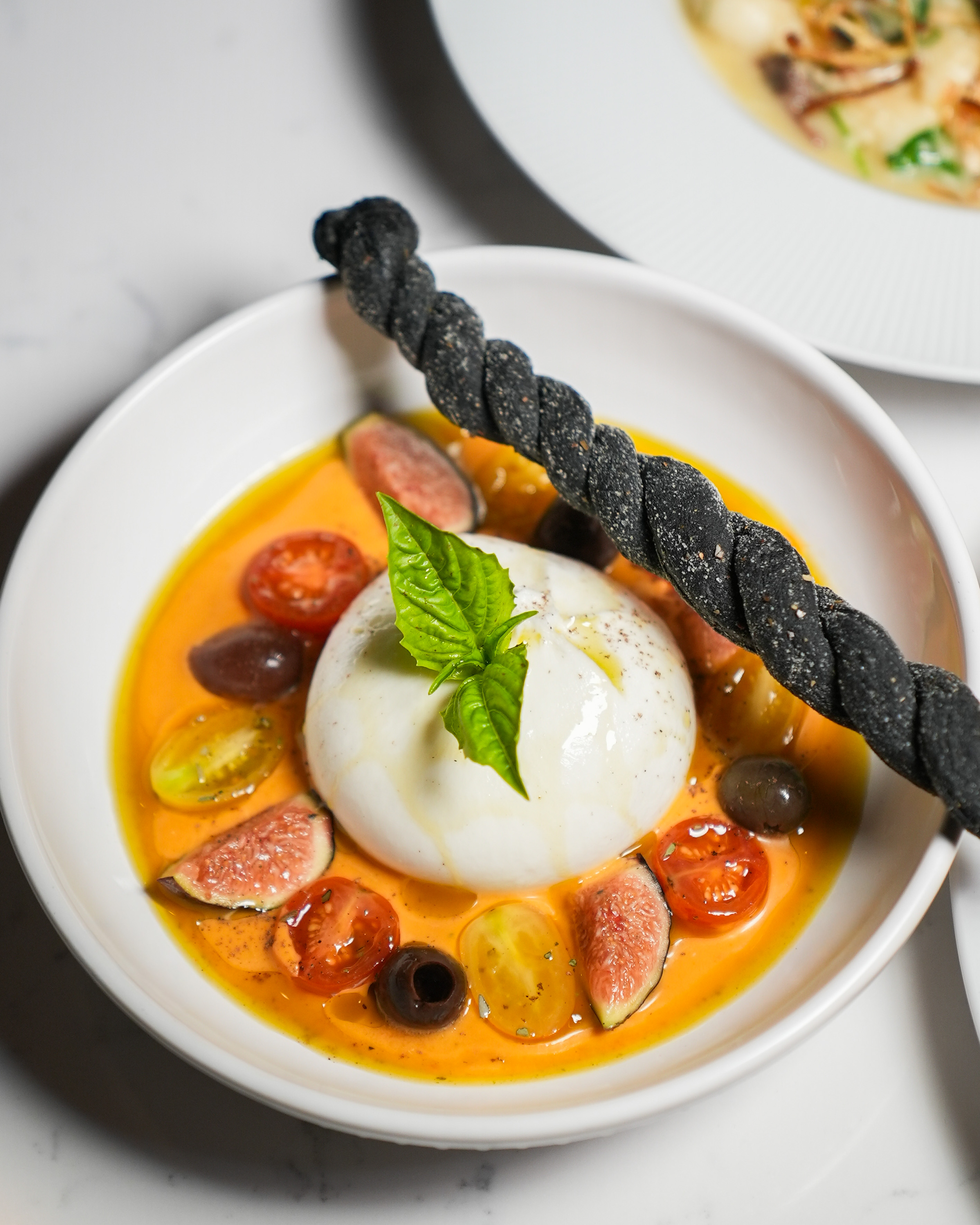 a bowl of soup with fruit and a black stick