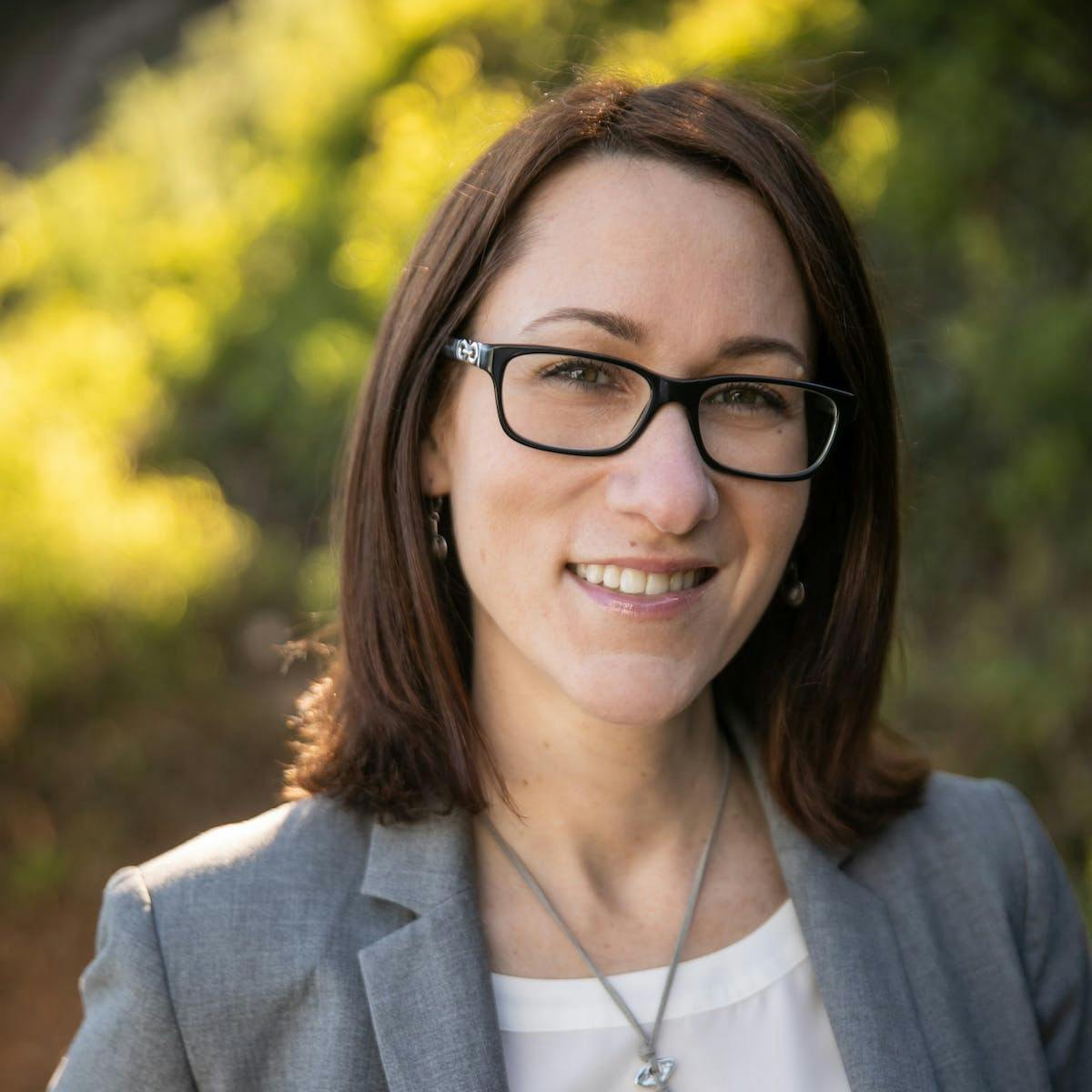 a woman wearing glasses and smiling at the camera