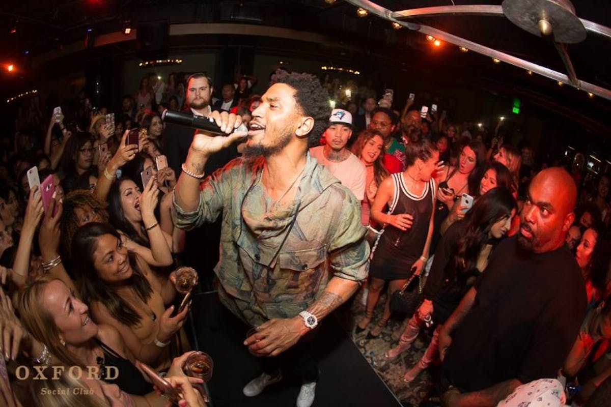 Trey Songz et al. standing on a stage in front of a crowd