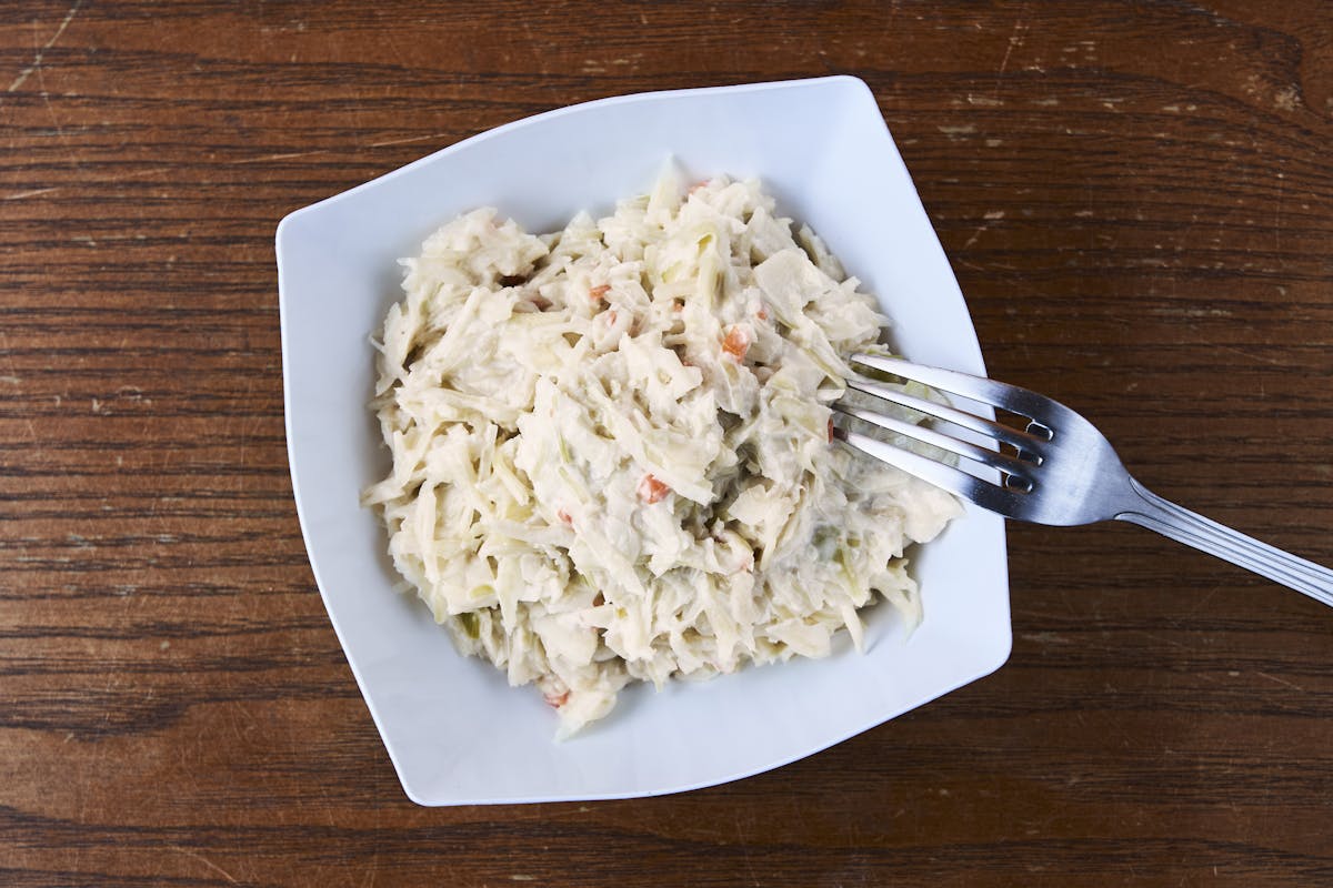 a spoon above a wooden table topped with a plate of food