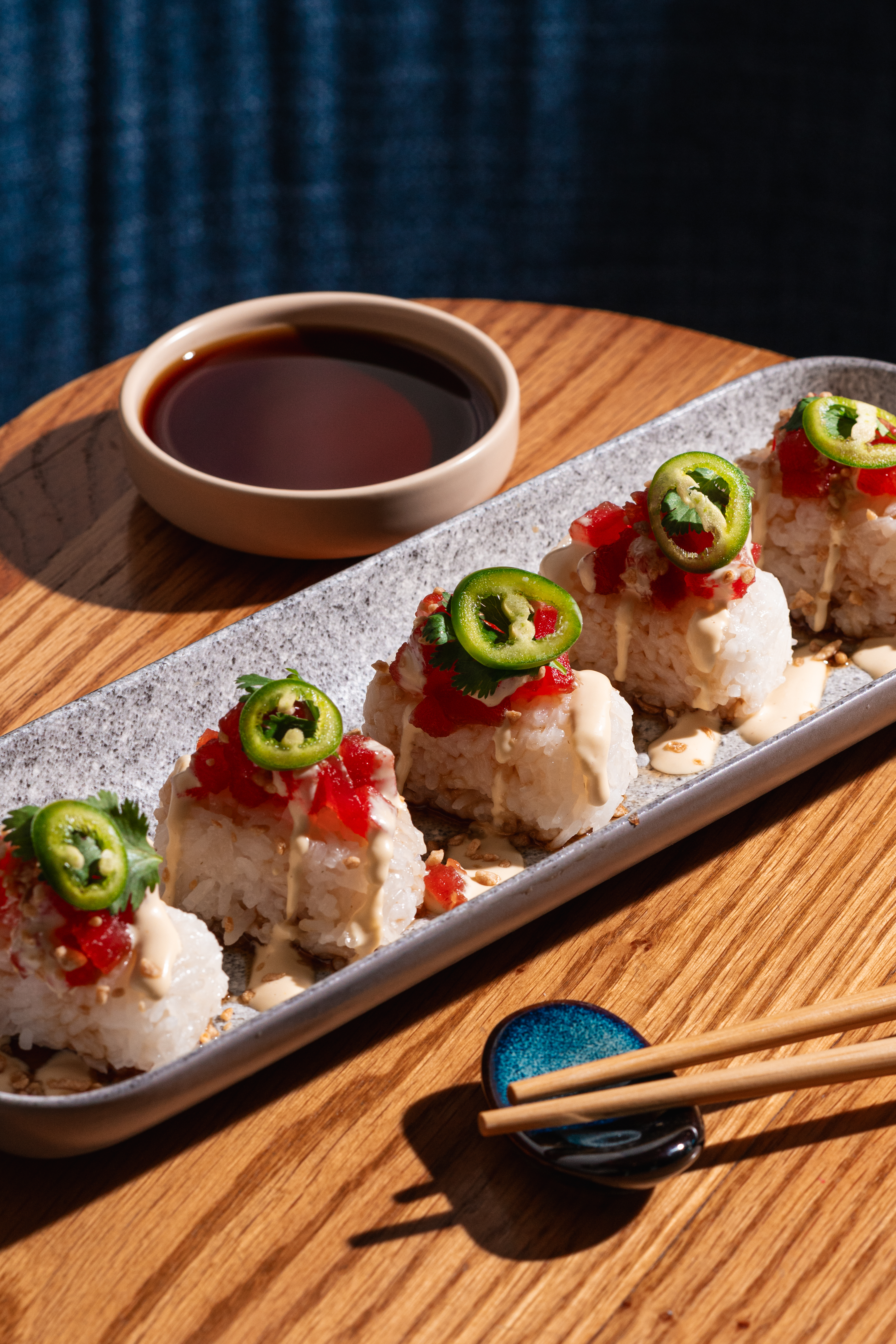 a plate of sushi with jalapenos and sauce