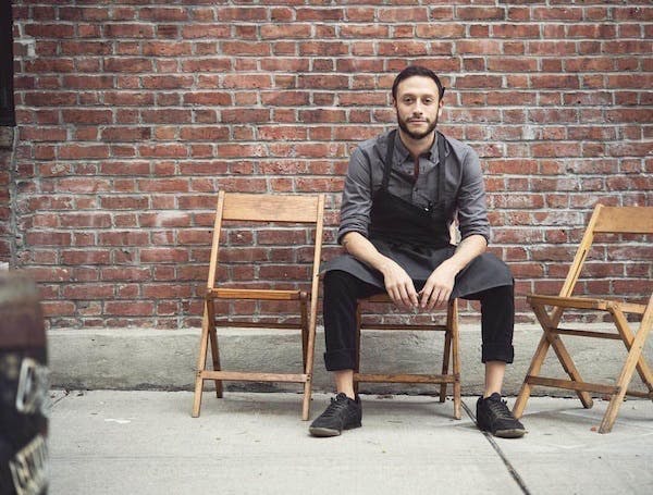 a man sitting on a bench next to a brick wall