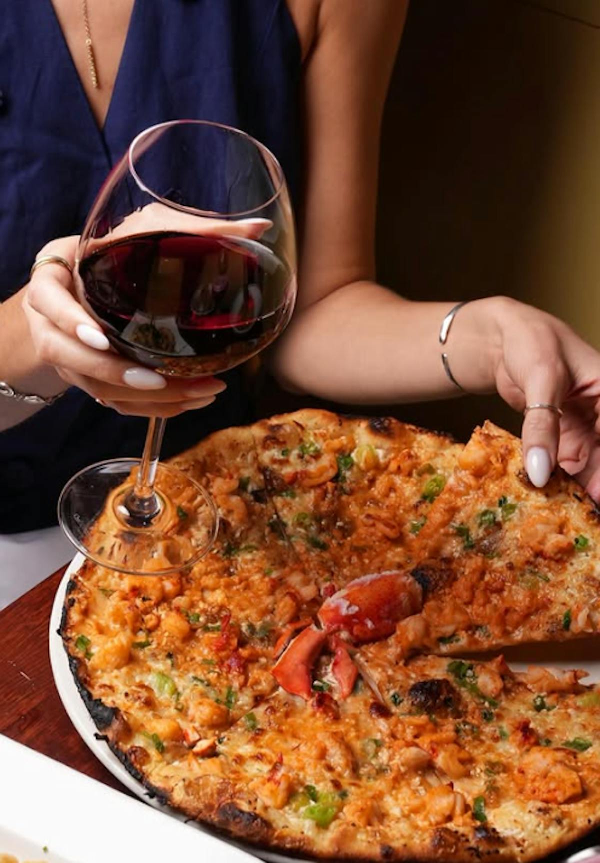 a woman sitting at a table with a plate of pizza