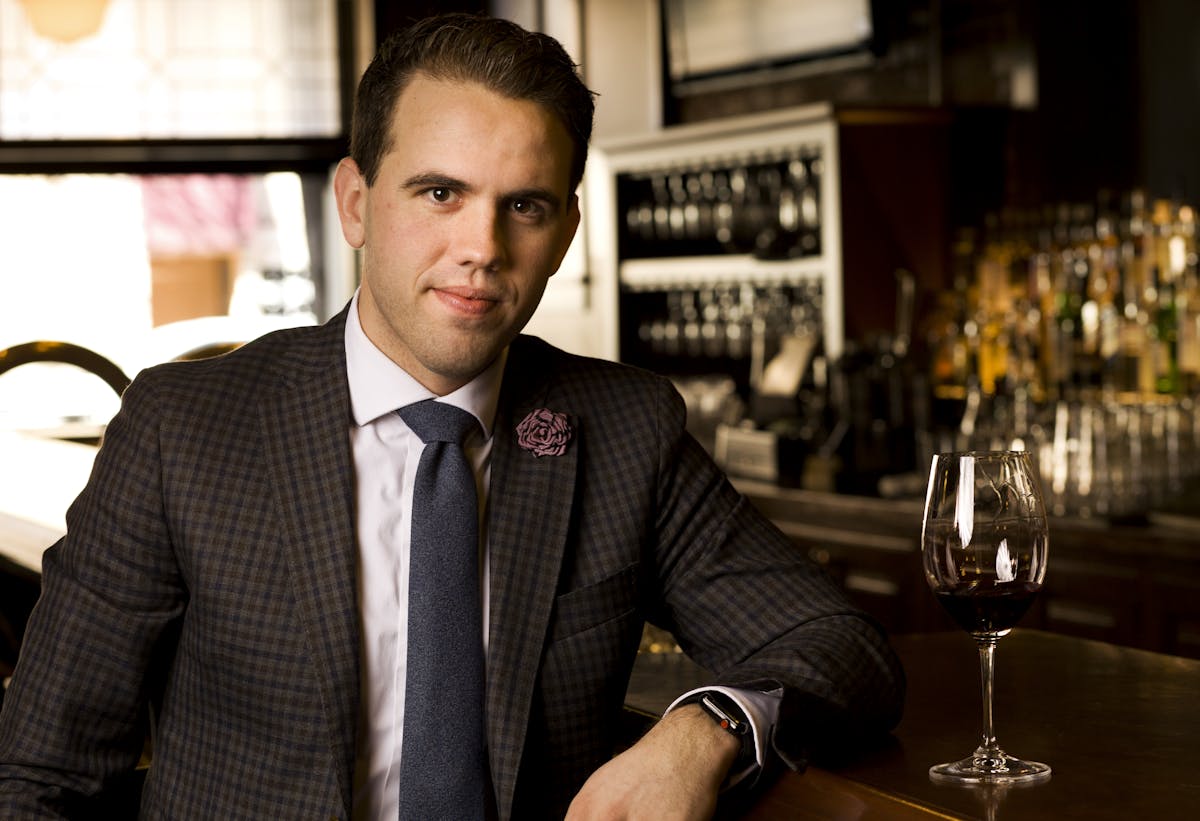 a man sitting at a table with wine glasses