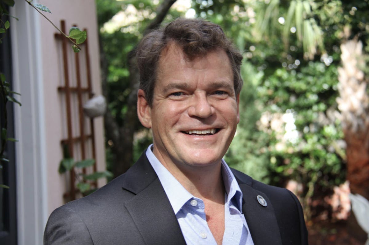 a man wearing a suit and tie smiling at the camera