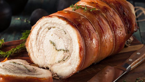 A picture of porchetta roast on a cutting board with porchetta slices in the foreground.
