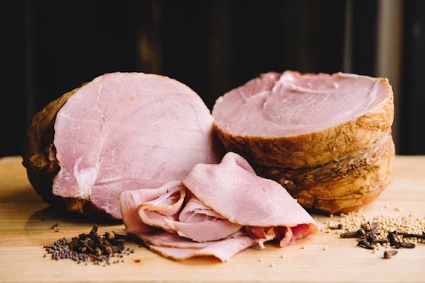 il porcellino salumis maple mustard glazed berkeley ham on a cutting board with slices in the foreground.