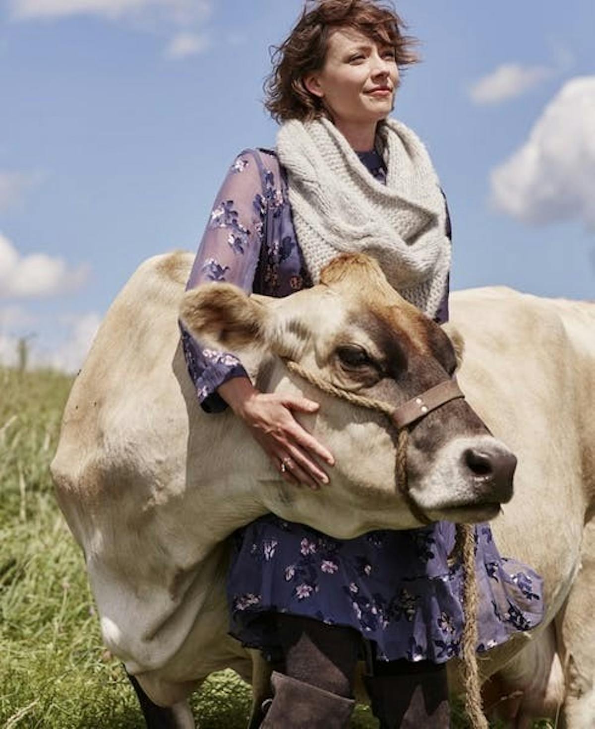 a woman, standing, embracing a cow's face