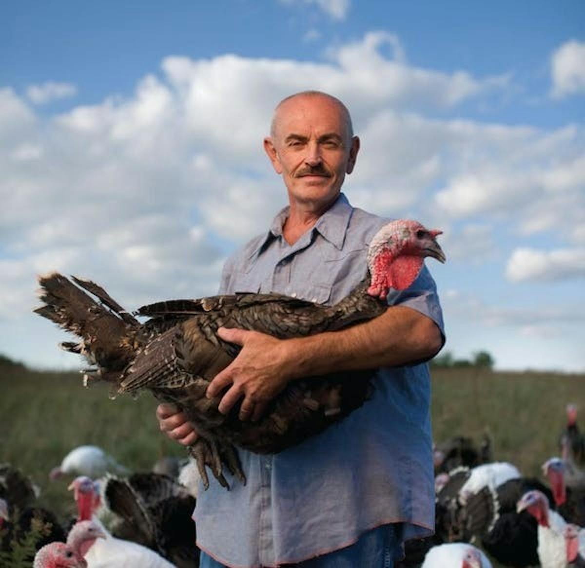a farmer holding a large turkey