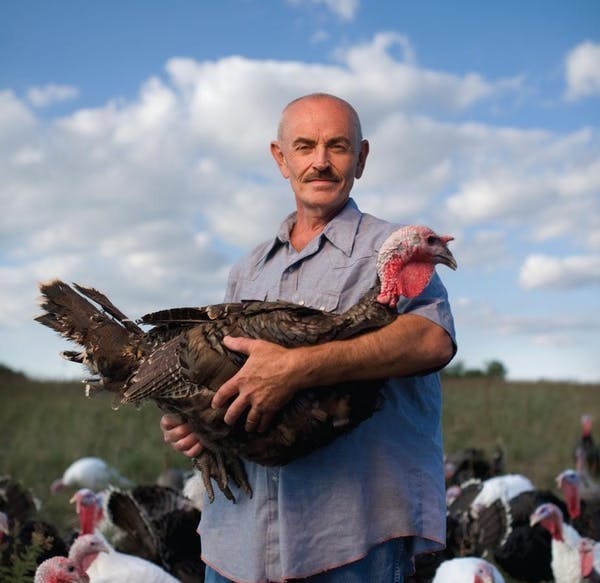 a farmer holding a large turkey