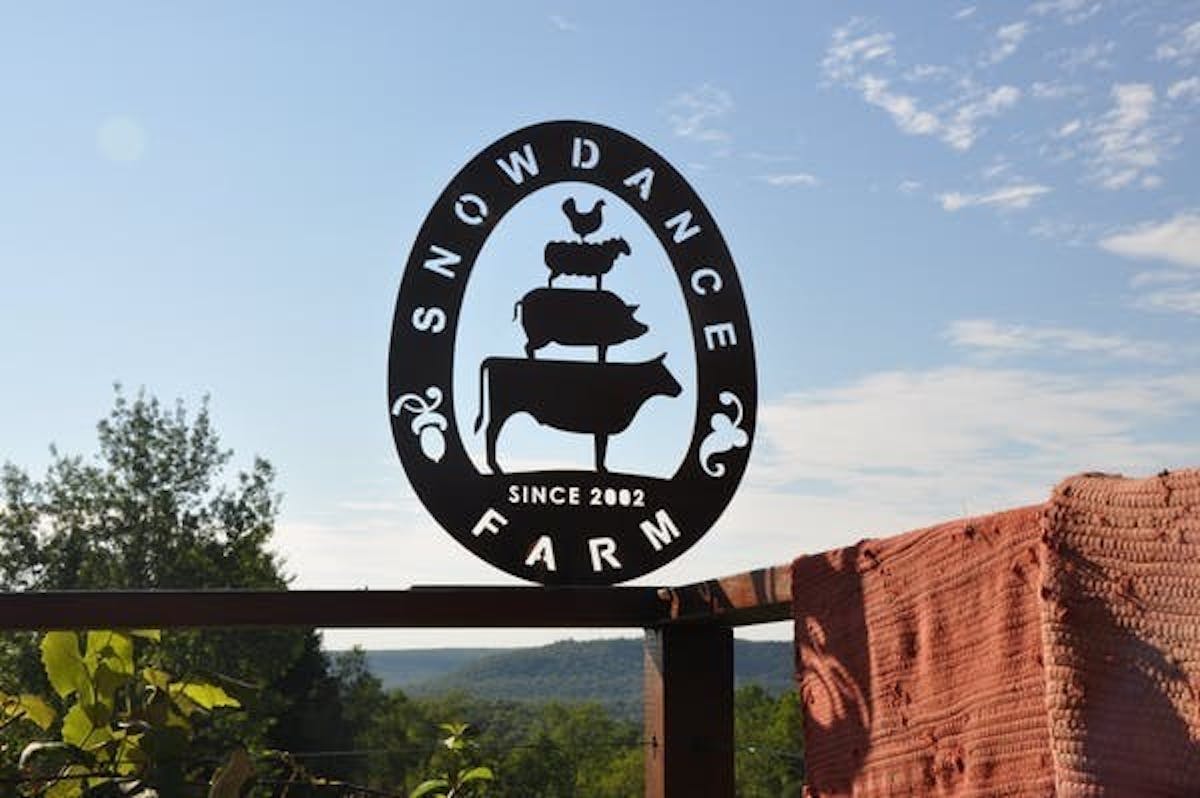 a farm fence with the Snowdance Farm sign with blue sky in the background