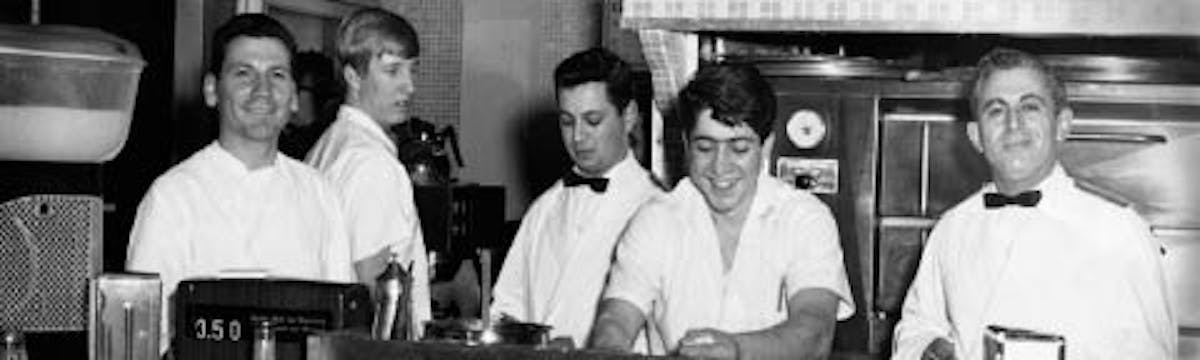 a group of people standing in a kitchen