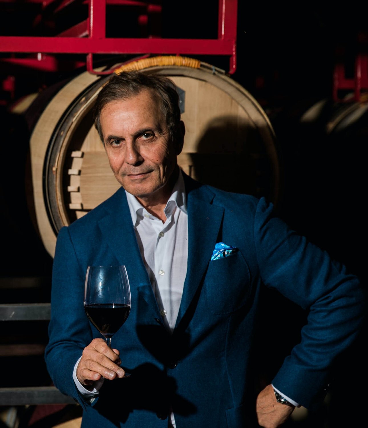 A PATRIMONY Estate proprietor holding a glass of red wine in the barrel room at the winery in Paso Robles