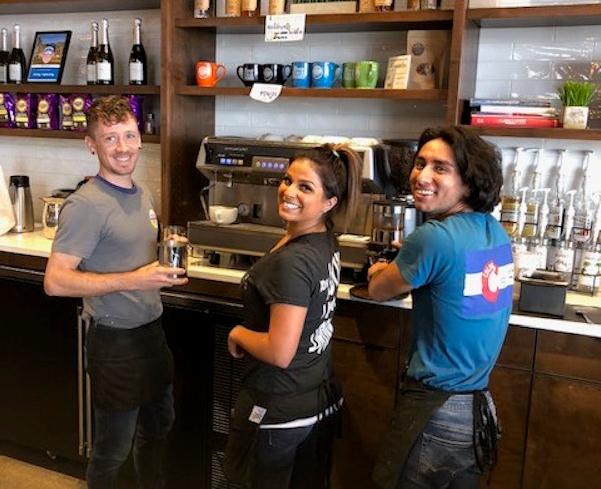 3 Staff Members Smiling by Shelves