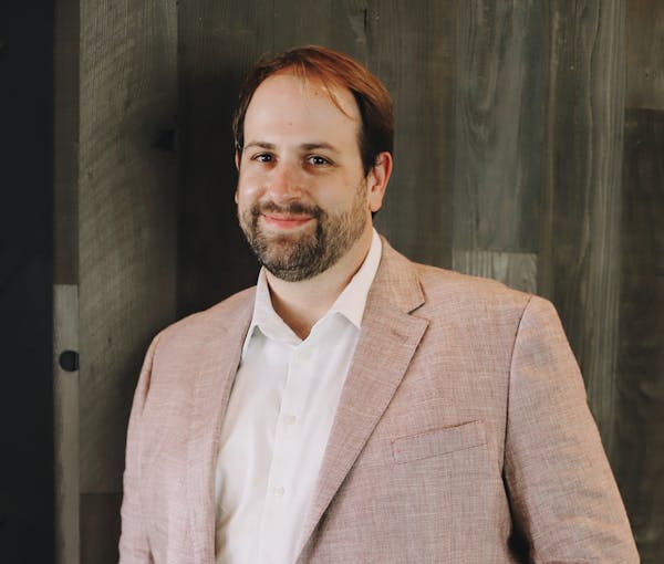 a man wearing a suit and tie smiling at the camera