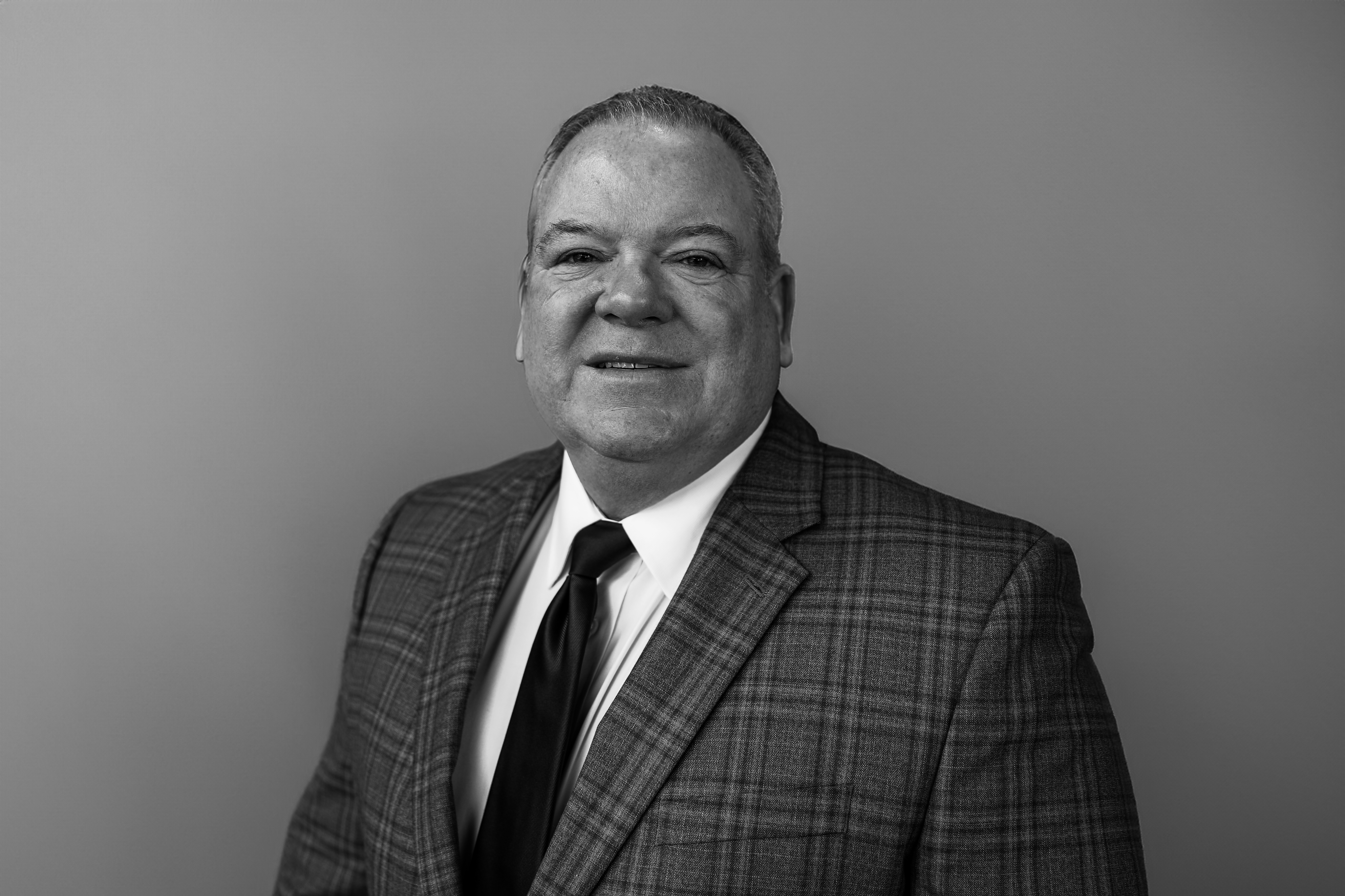 a man wearing a suit and tie smiling at the camera