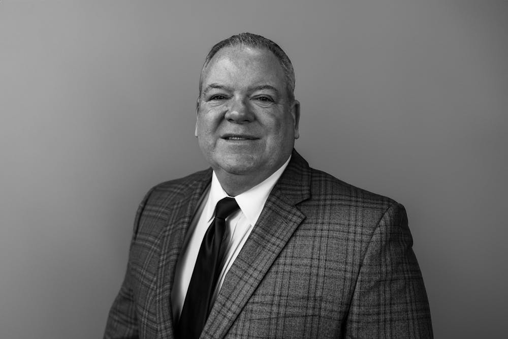 a man wearing a suit and tie smiling at the camera