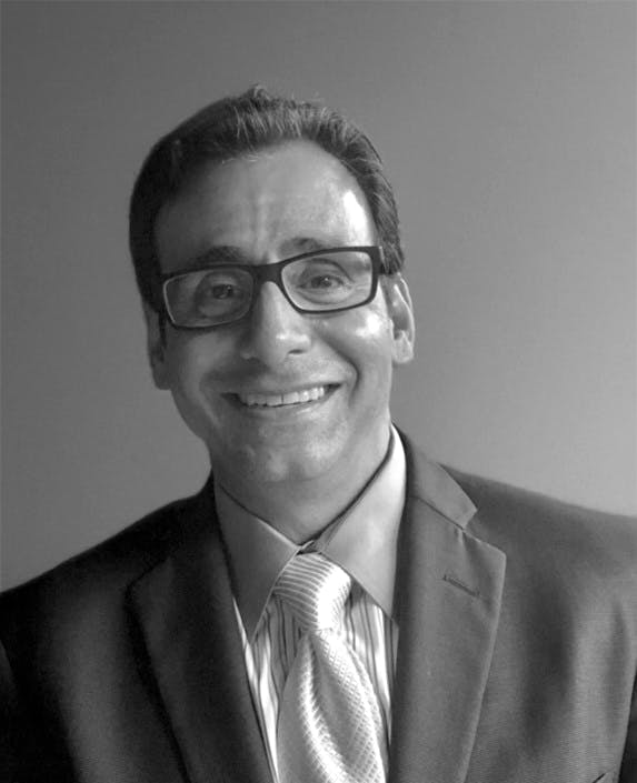 a man wearing a suit and tie smiling at the camera