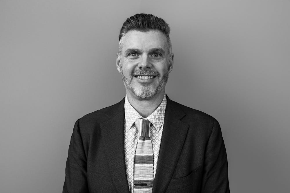 a man wearing a suit and tie smiling at the camera