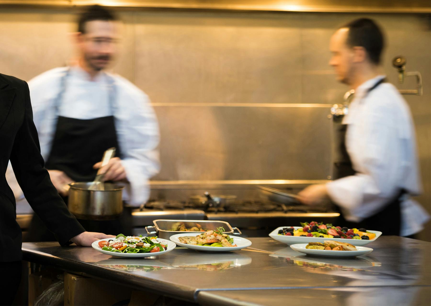 a group of people standing in a kitchen preparing food