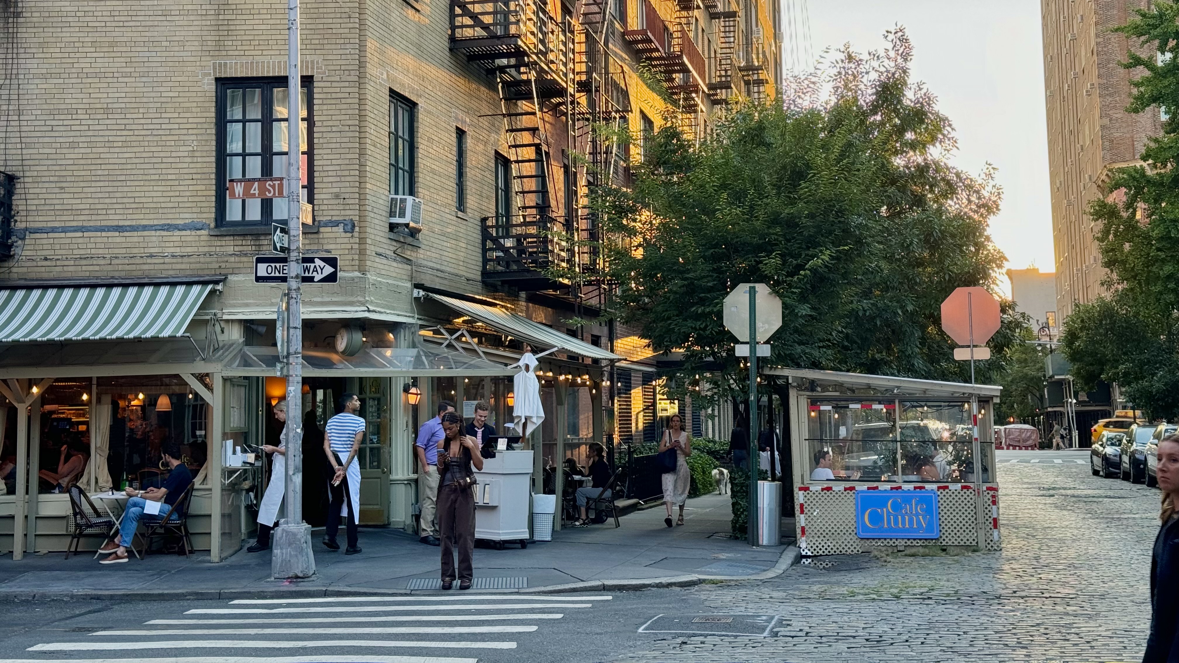 tourists and neighbors walking towards the welcoming door of cafe cluny on a charming cobble stone street in the lovely west village in the morning sun 