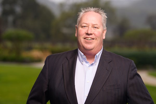 a man wearing a suit and tie smiling at the camera