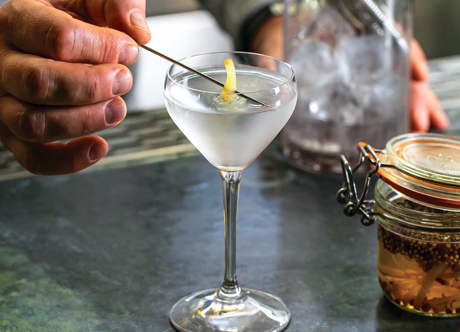 a person holding a pick in a martini glass