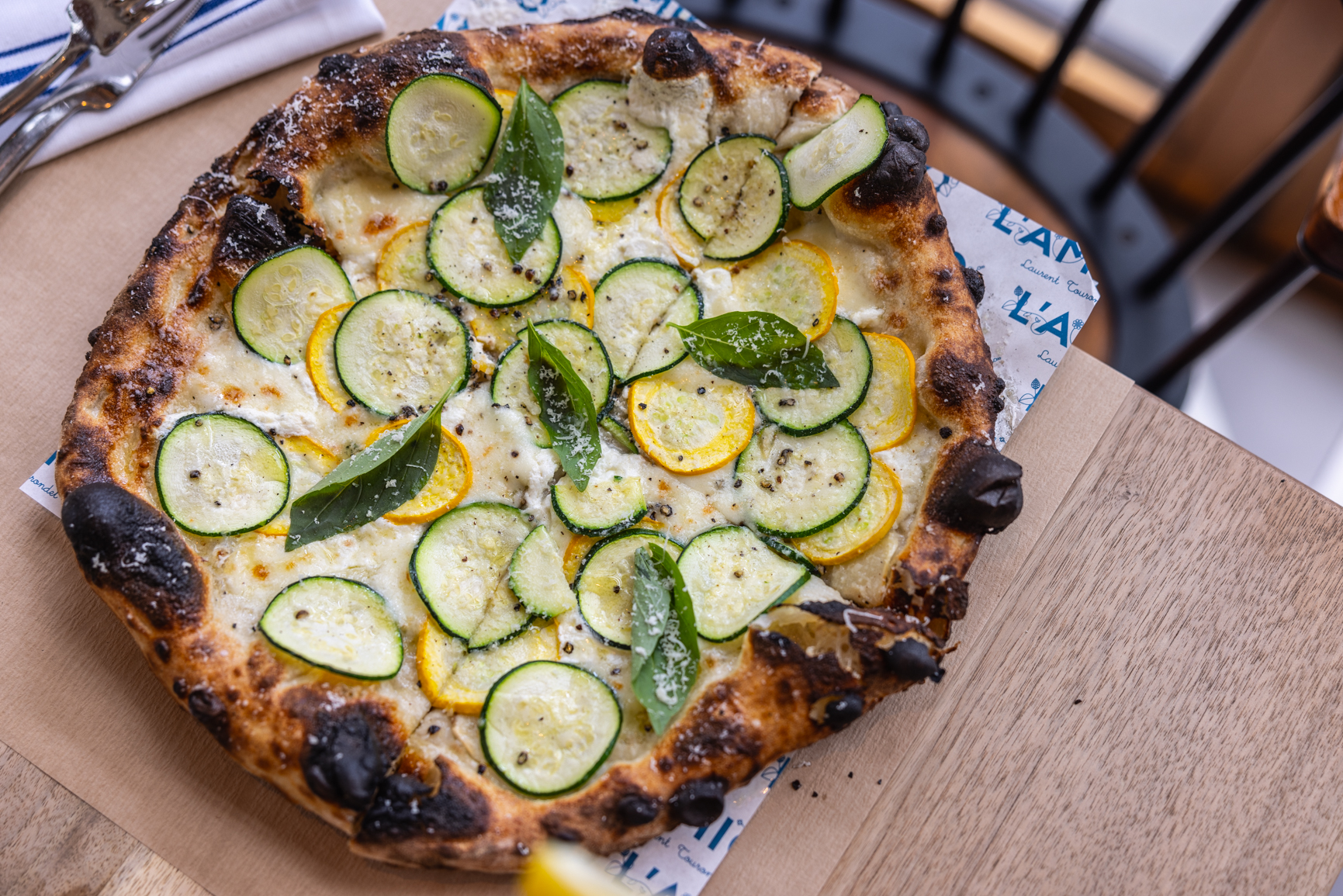 a pizza with zucchini and yellow squash on a table