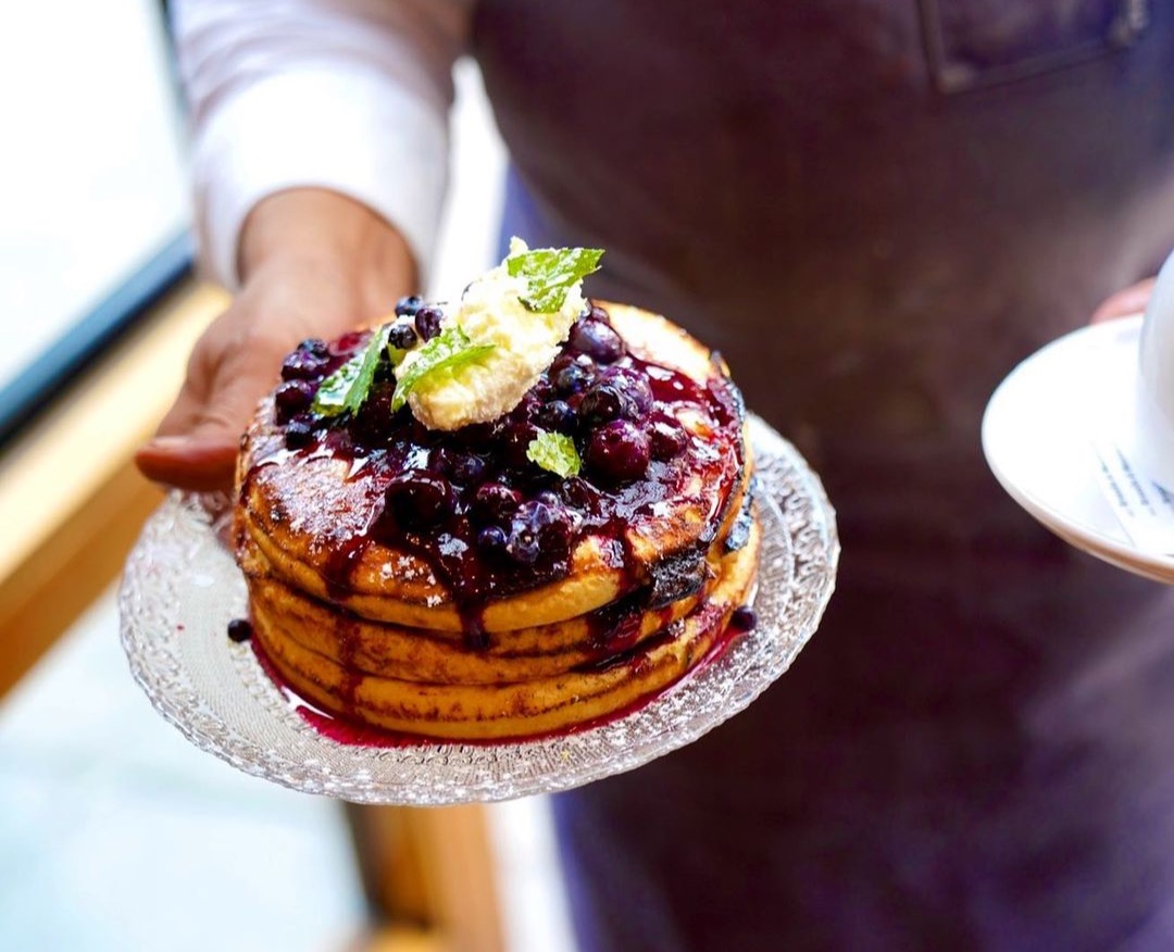 a person holding a plate of pancakes