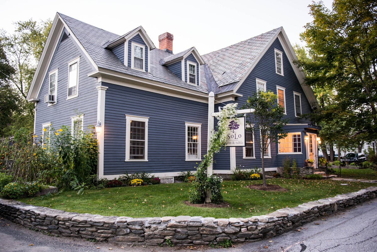 a large brick building with grass in front of a house