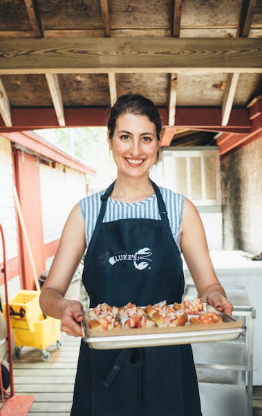 a woman standing in front of a tray of food