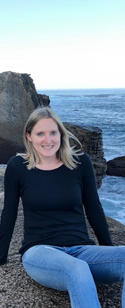 a woman sitting next to a body of water