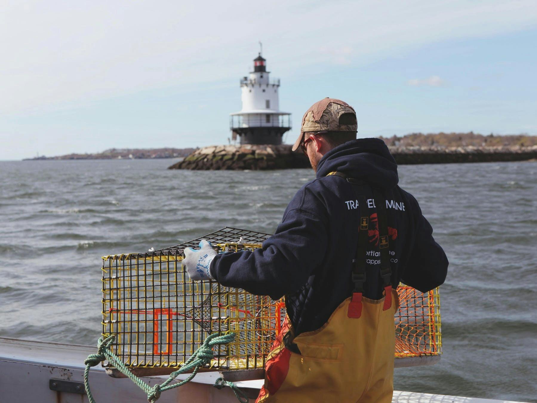 a man fishing with a lighthouse in the background