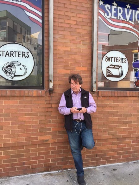 Alan standing against wall