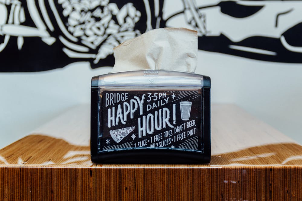 a napkin dispenser and a happy hour sign on it