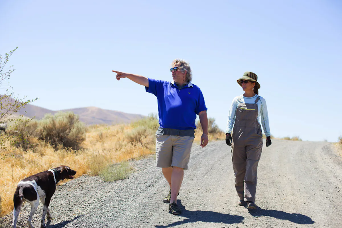 a man and a dog walking on a dirt road