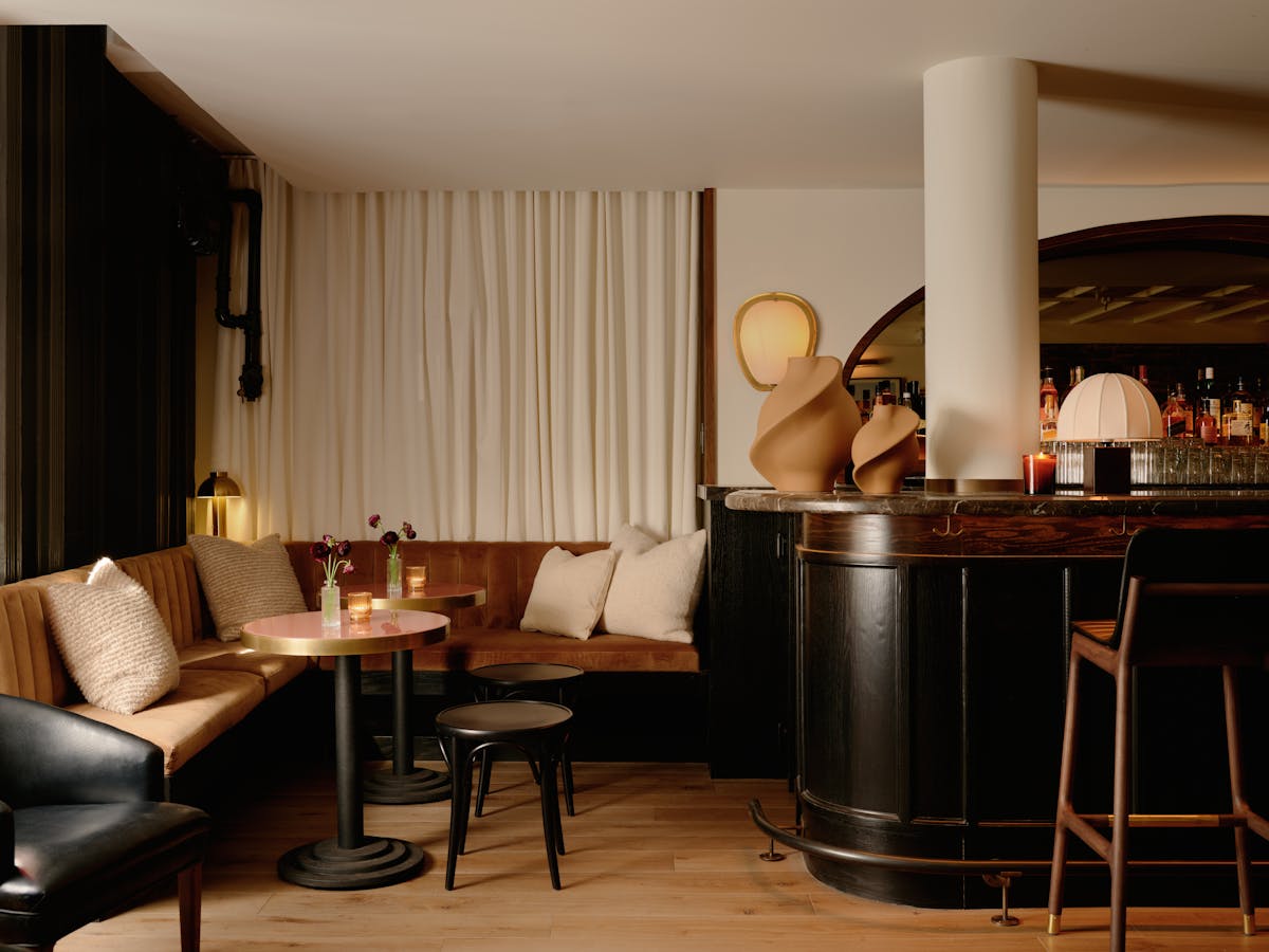 a plush velvet banquette with bistro tables next to an elegant bar