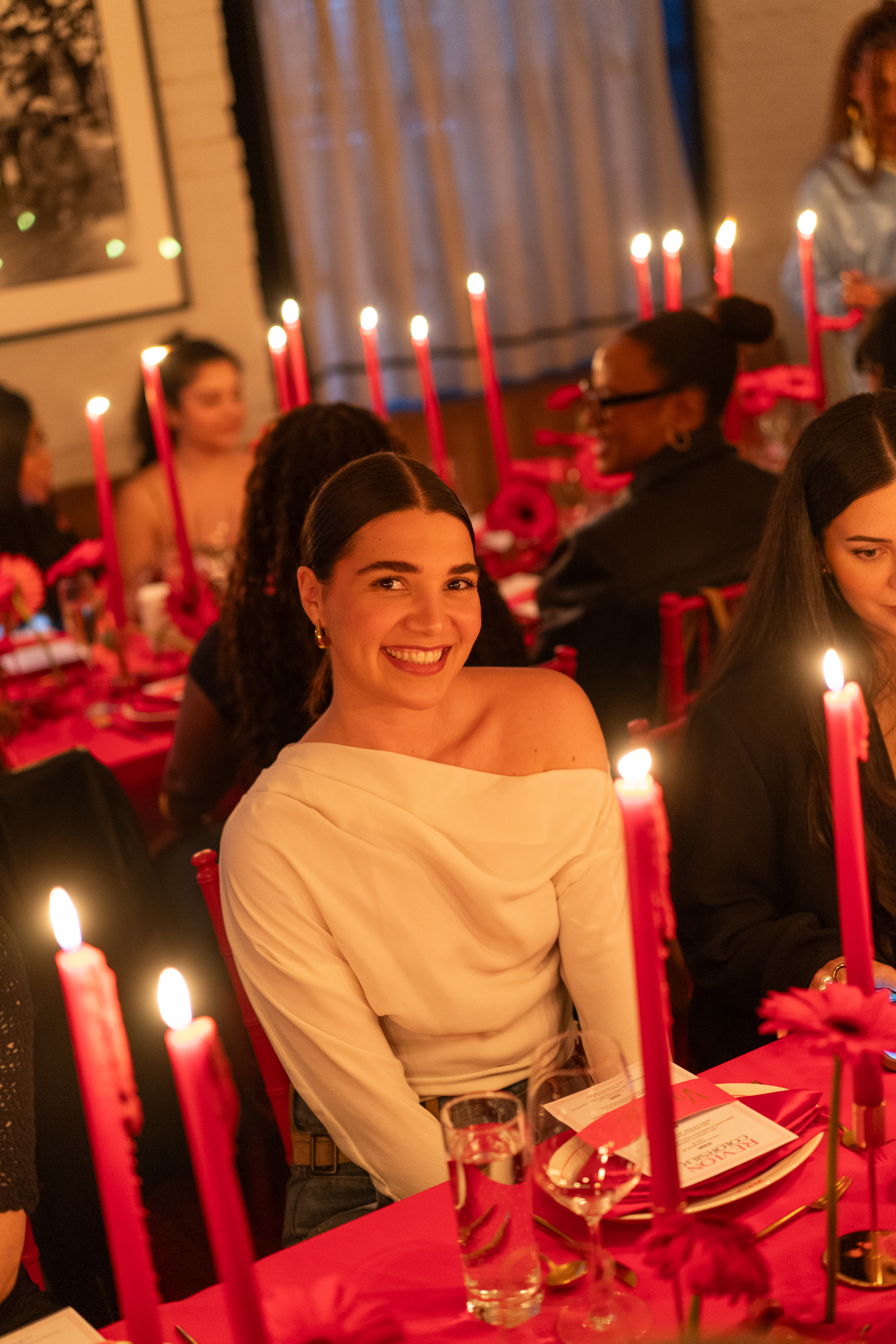 a person sitting at a table with a birthday cake with lit candles