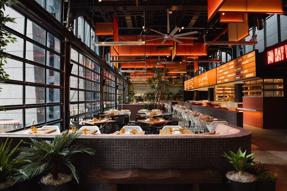 a restaurant with table seating and orange lighting.