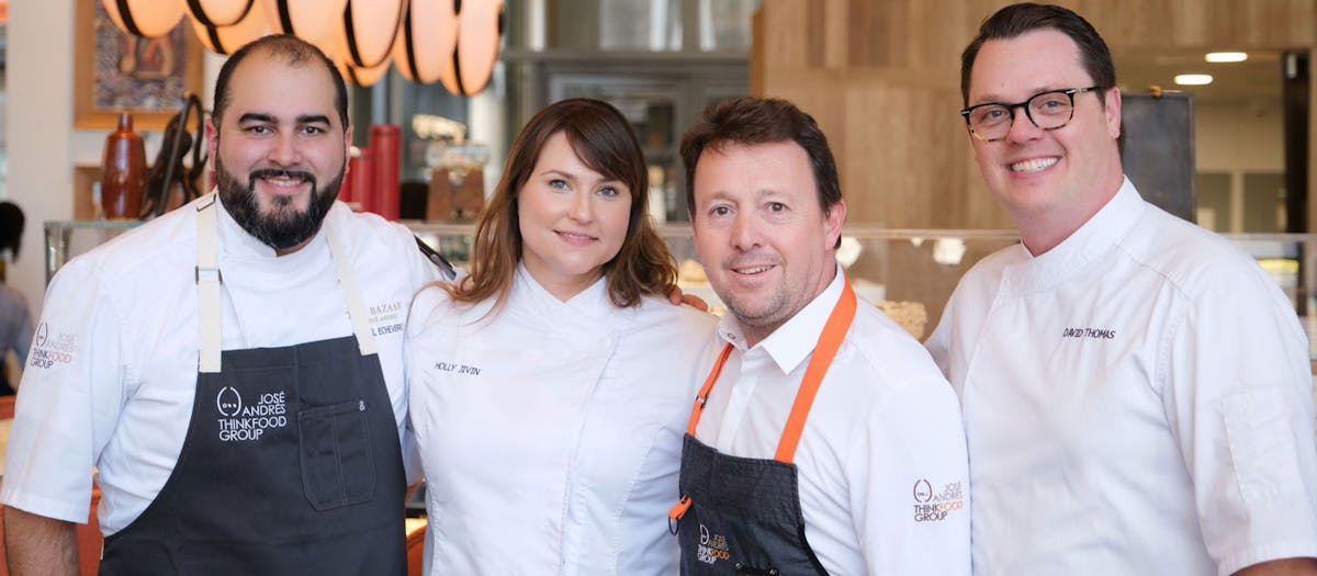 Four chefs smiling and posing together
