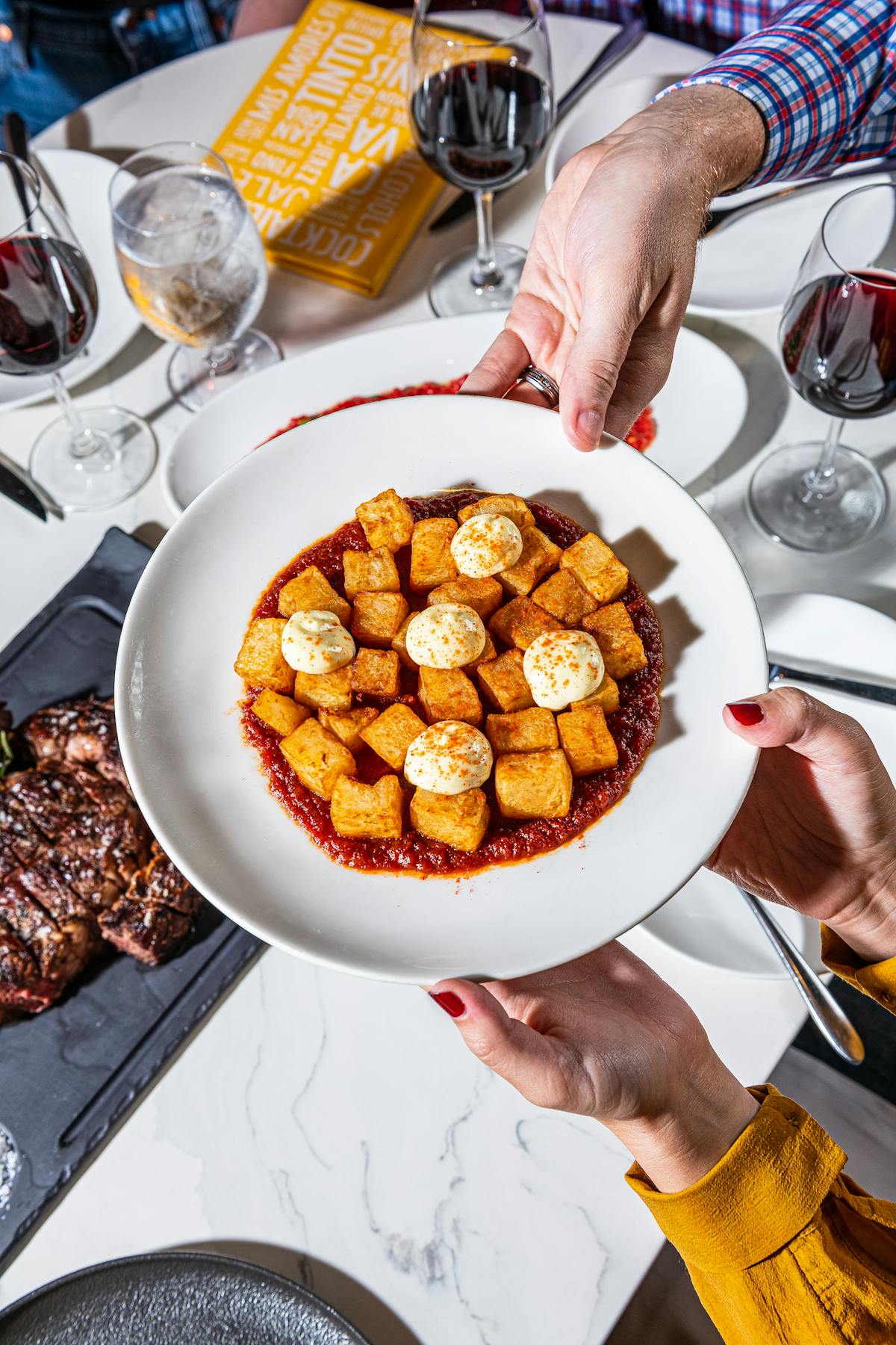 a plate of fried potatoes, tomato sauce, and white sauce.