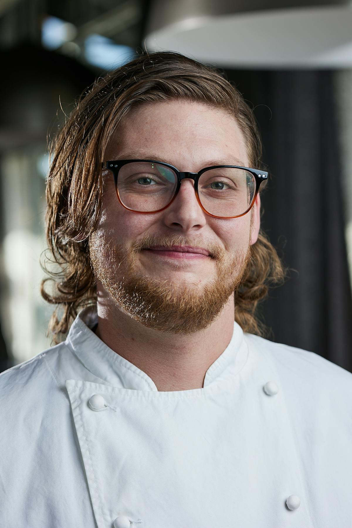 a man wearing glasses and smiling at the camera