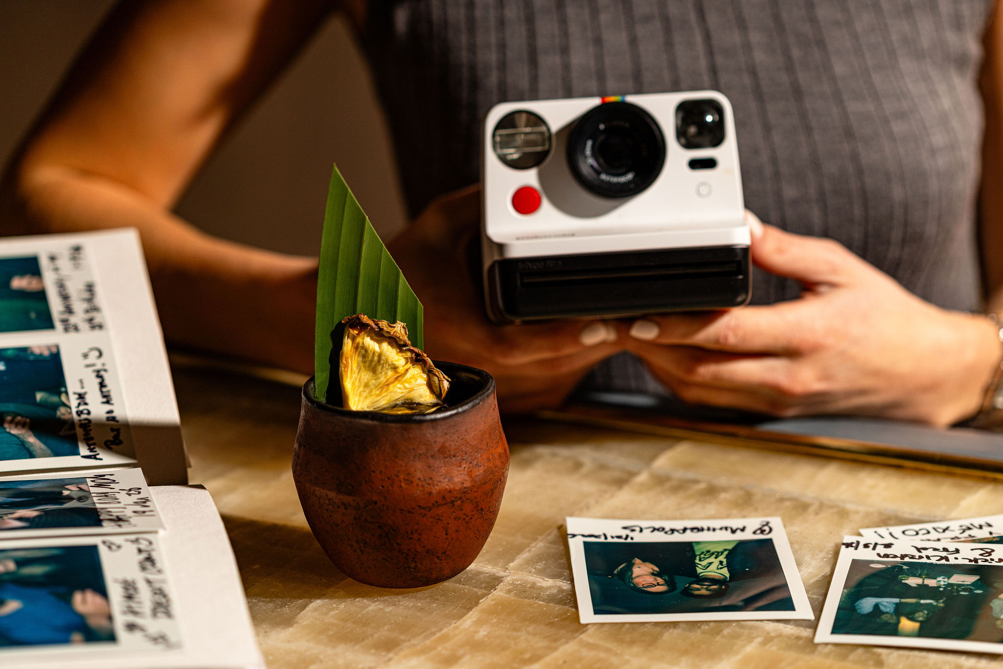a person holding a camera and a cup with a leaf in it