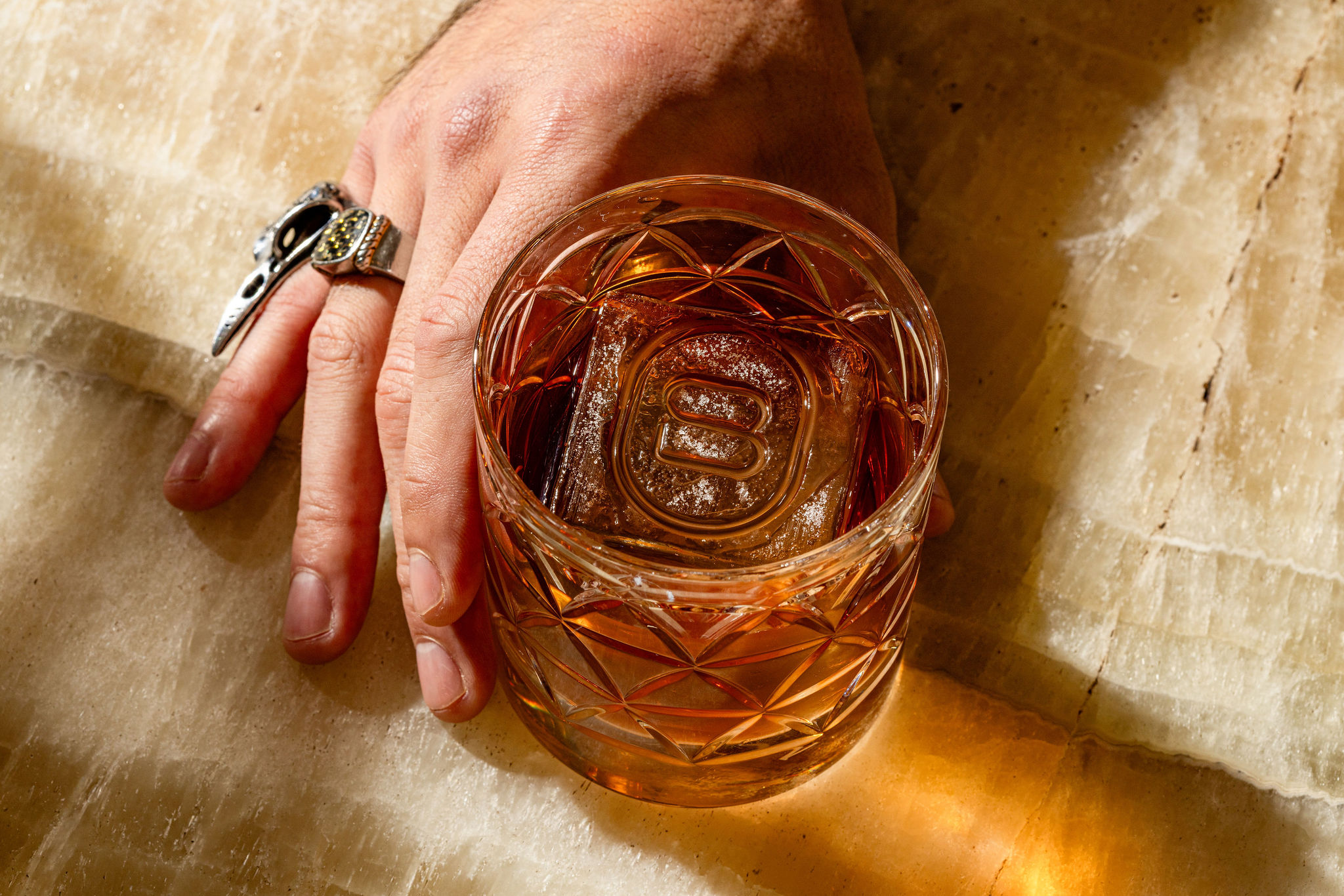 a hand holding a glass of amber liquid