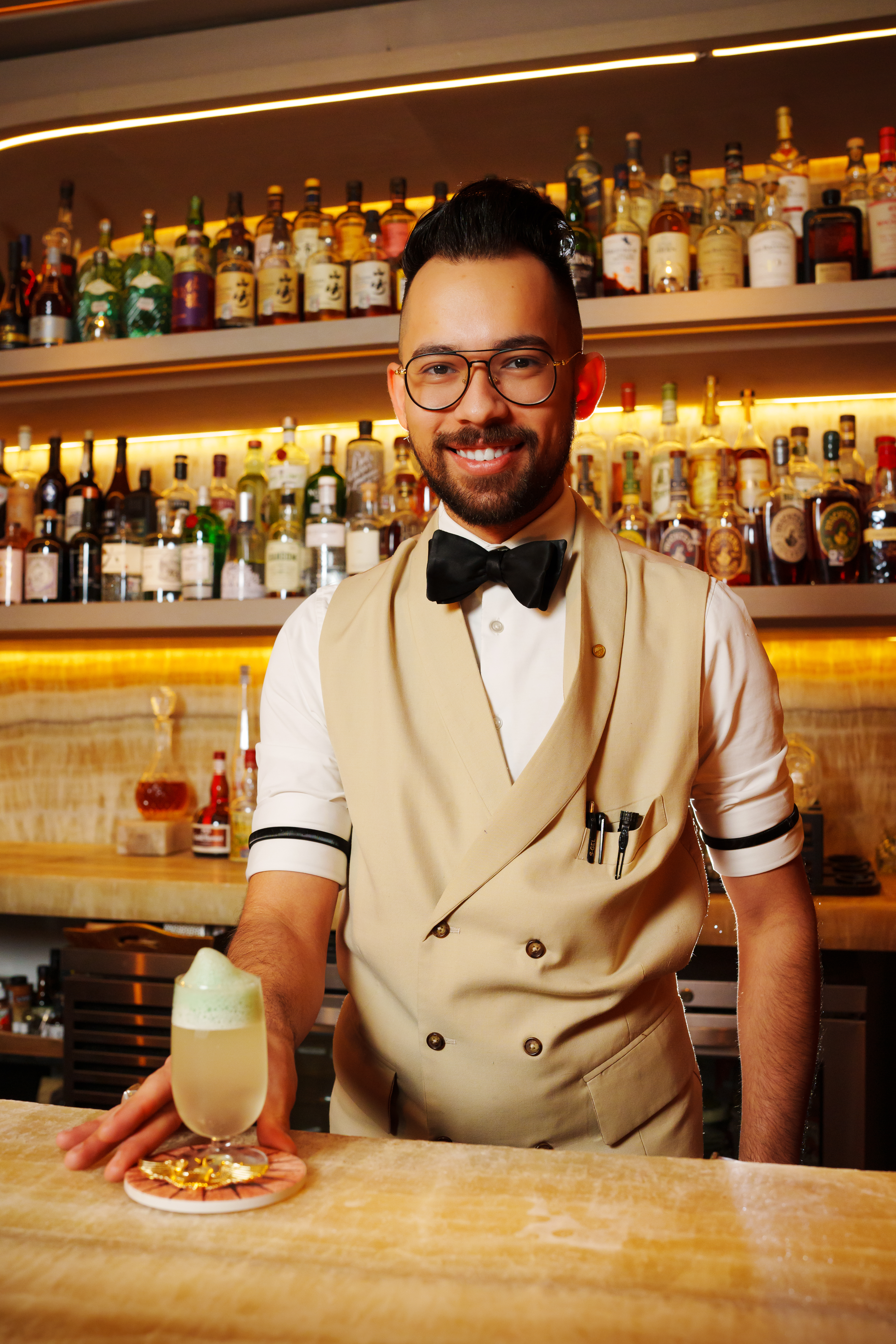 a man in a vest and bow tie holding a drink