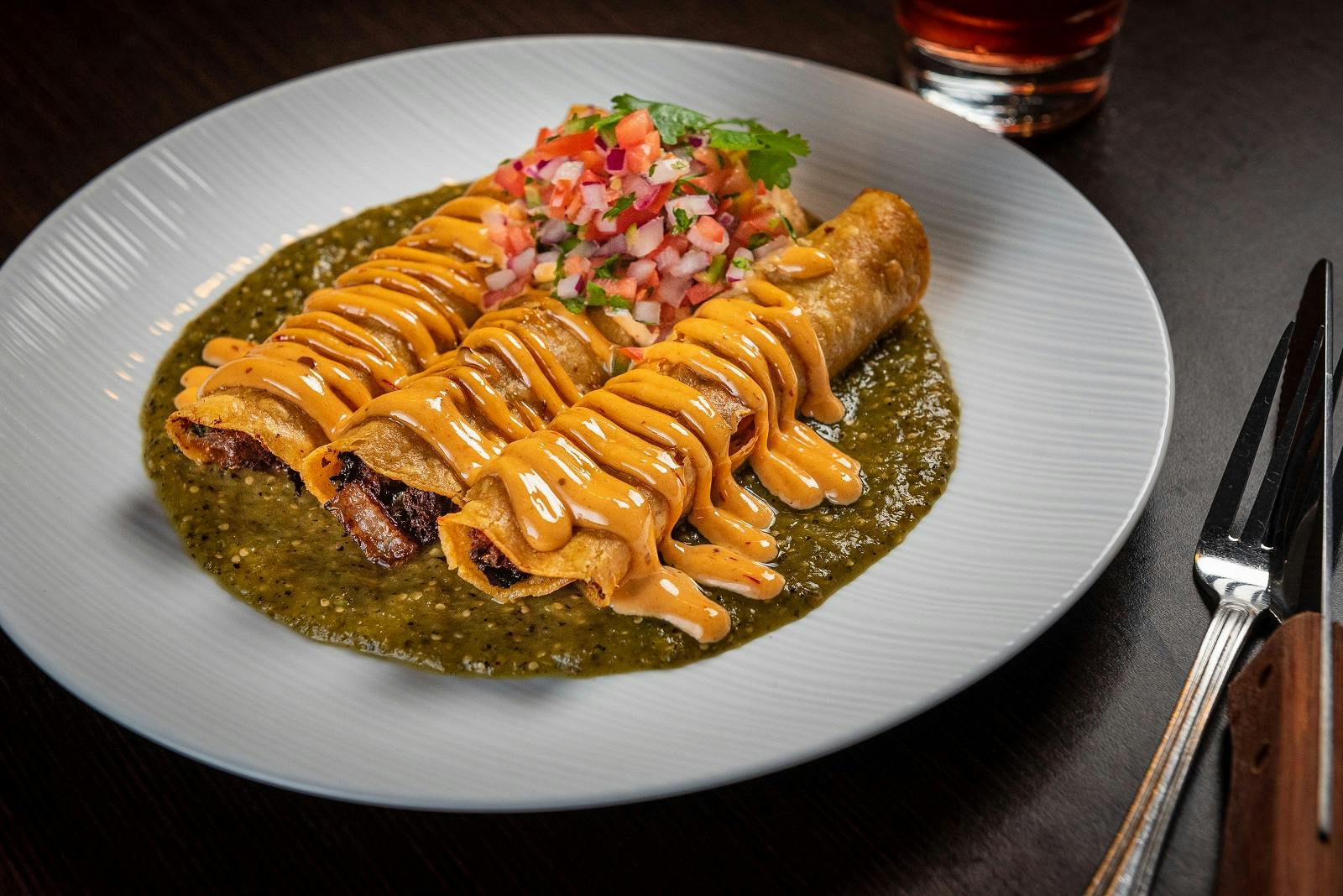 taquitos with sauce on a plate