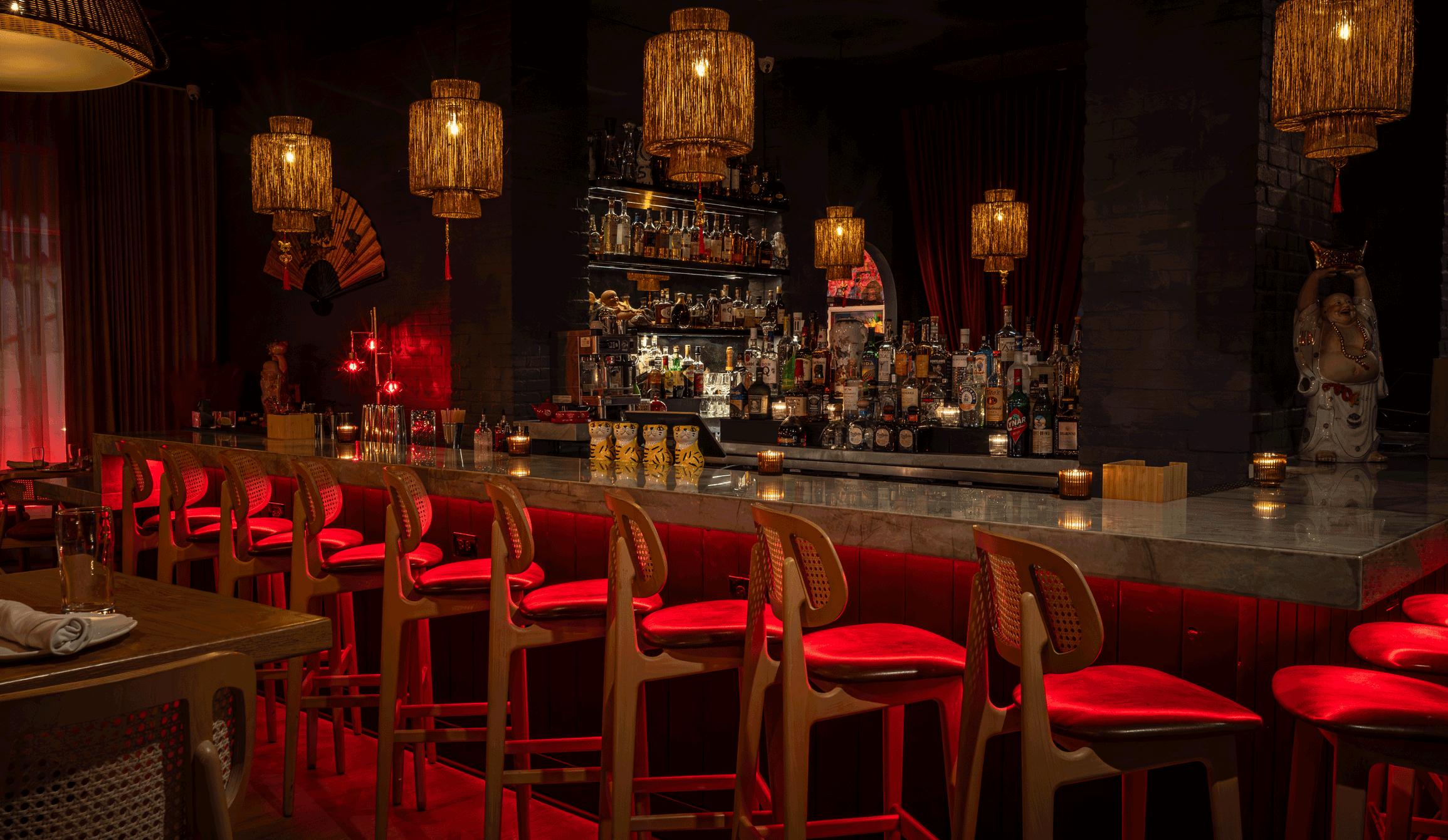 a bar with red chairs and lights
